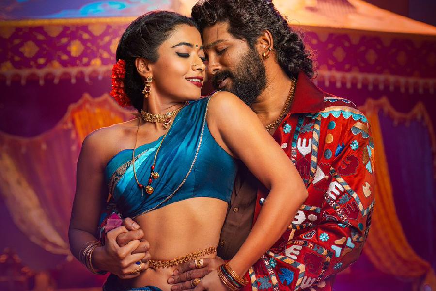 A couple in traditional attire sharing an intimate dance moment, set against a colorful backdrop.